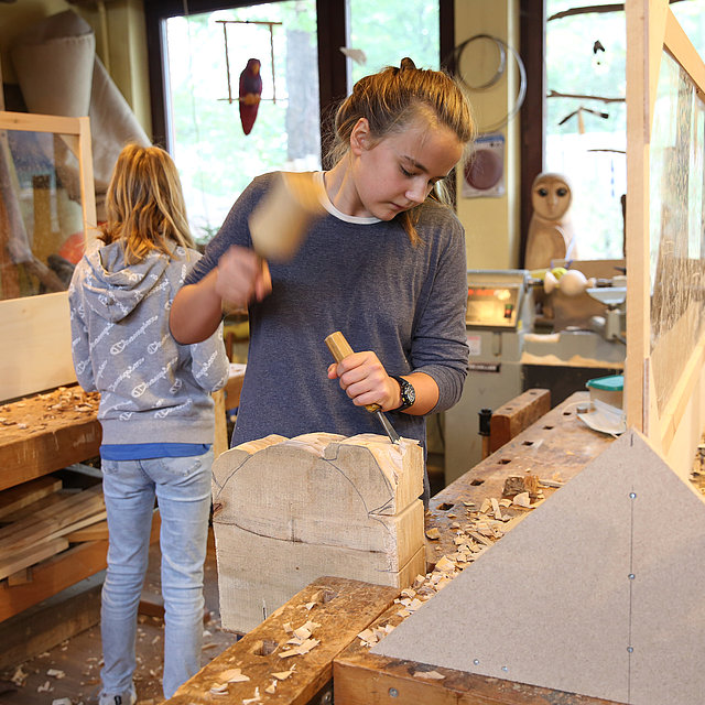 Freiwillige bearbeitet Holzklotz im FSJ in der Schule