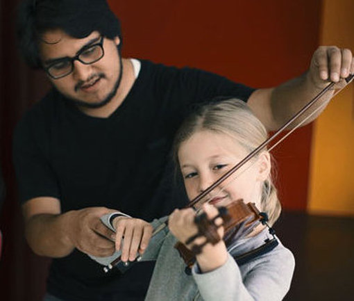 Freiwilliger bringt Kindern Geige spielen bei beim FSJ in Bayern