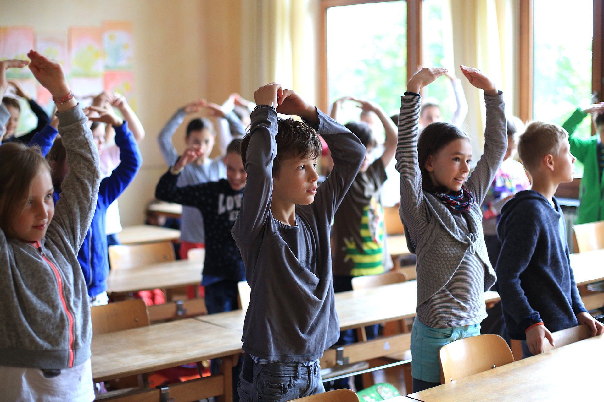 Kinder in der Klasse bewegen sich zum Morgenspruch im FSJ in der Schule