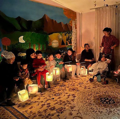Menschengruppe mit Laternen sitzen gemütlich im Wohnzimmer beim FSJ Kirgistan