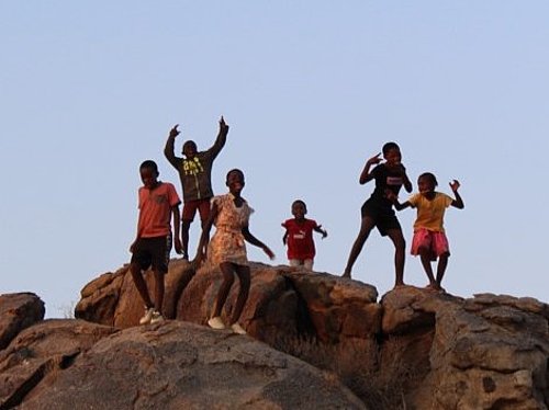 Kinder stehen auf einem Felsen und tanzen beim FSJ in Tansania