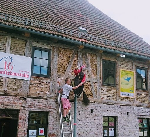Junge steht auf einer Leiter, angelehnt an ein Haus der Zukunftsbaustelle beim FSJ in Sachsen-Anhalt.