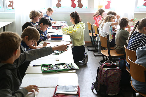 Klassenhelferin hilft Schülern bei den Aufgaben