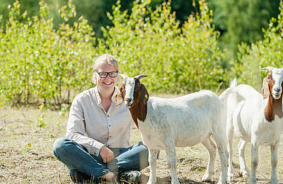 Junge Frau mit Ziege im Gras im FSJ Bauernhof
