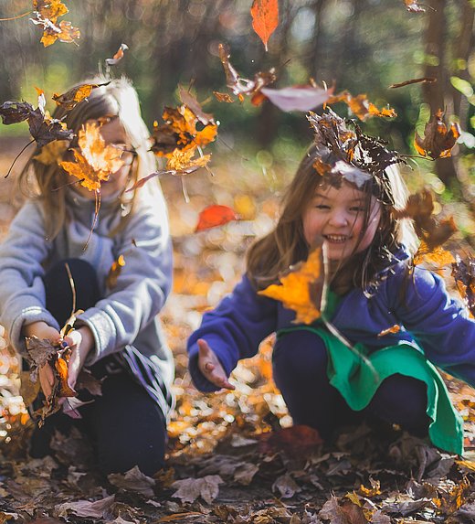 Kinder spieln im Herbst mit Blättern im FSJ Kindergarten