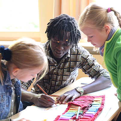 Freiwilliger hilft zwei Schülerinnen beim FSJ Schule