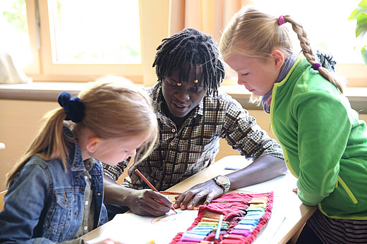 Freiwilliger hilft zwei Schülerinnen beim FSJ Schule