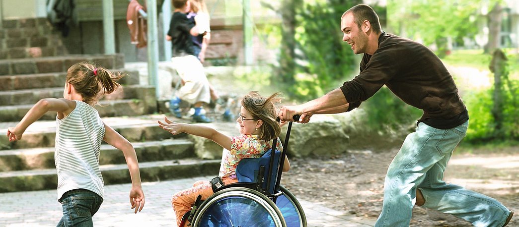 Freiwilliger spielt mit Kind im Rollstuhl beim FSJ Heilpädagogik.