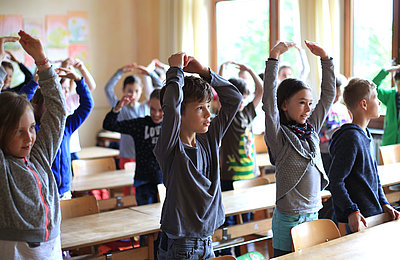 Kinder in der Klasse bewegen sich zum Morgenspruch im FSJ in der Schule