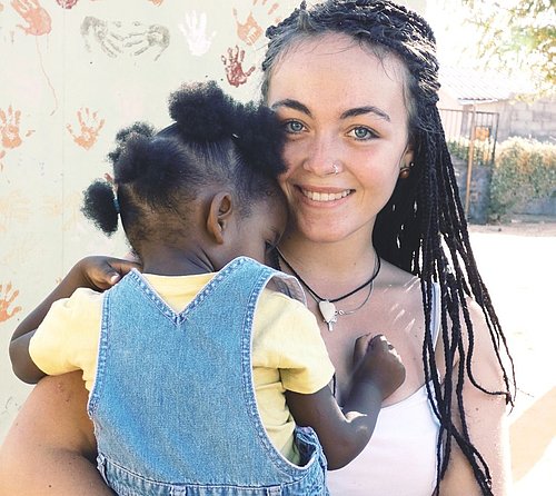 Freiwillige hält ein kleines Mädchen auf dem Arm bei ihrem FSJ in Namibia