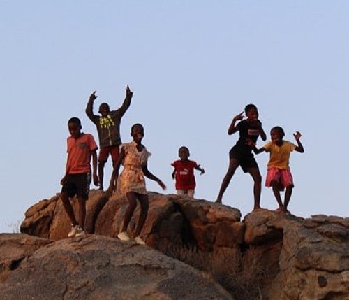 Kinder stehen auf einem Felsen und tanzen beim FSJ in Tansania