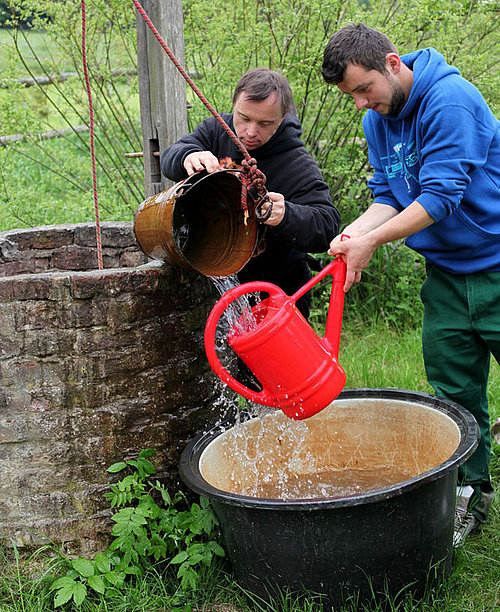 Auffüllen einer Gießkanne am Brunnen beim FSJ