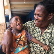 Pedagogía curativa Ghana Una mujer sostiene en brazos a un niño que ríe