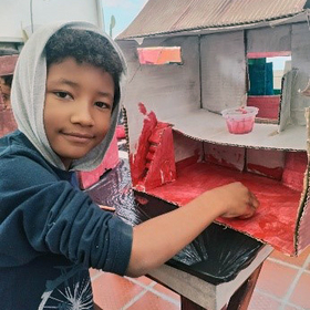 Kind bastelt ein Haus aus Pappe im Rahmen von Notfallpädagogik in Kolumbien