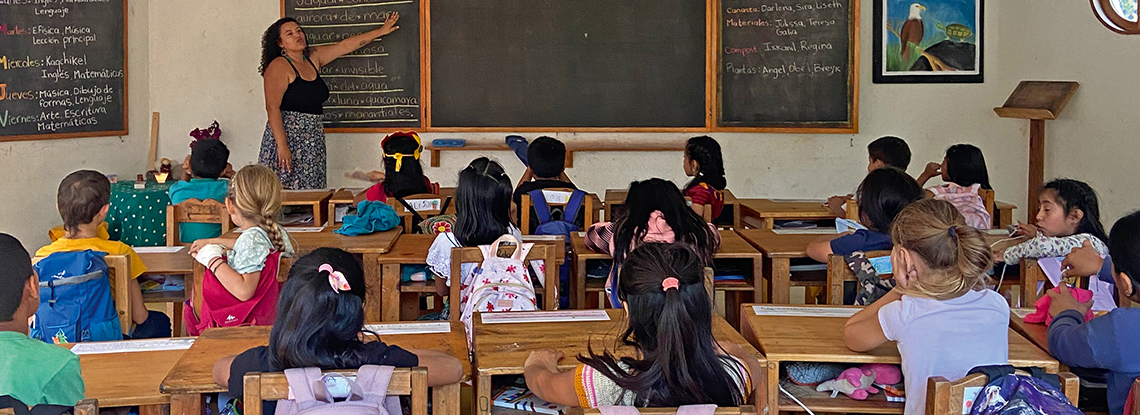 Eine Schulklasse in Guatemala, die Lehrerin zeigt etwas an der Tafel.