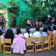Waldorf Ozeanien Rapa Nui Kinder sitzen draußen auf Stühlen und hören einer Erzählerin und einer Musikgruppe zu