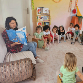 Frau liest Kindern Buch im Kinderschutzzentrum vor