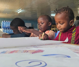 Notfallpädagogik Kenia Drei Kinder malen am Tisch
